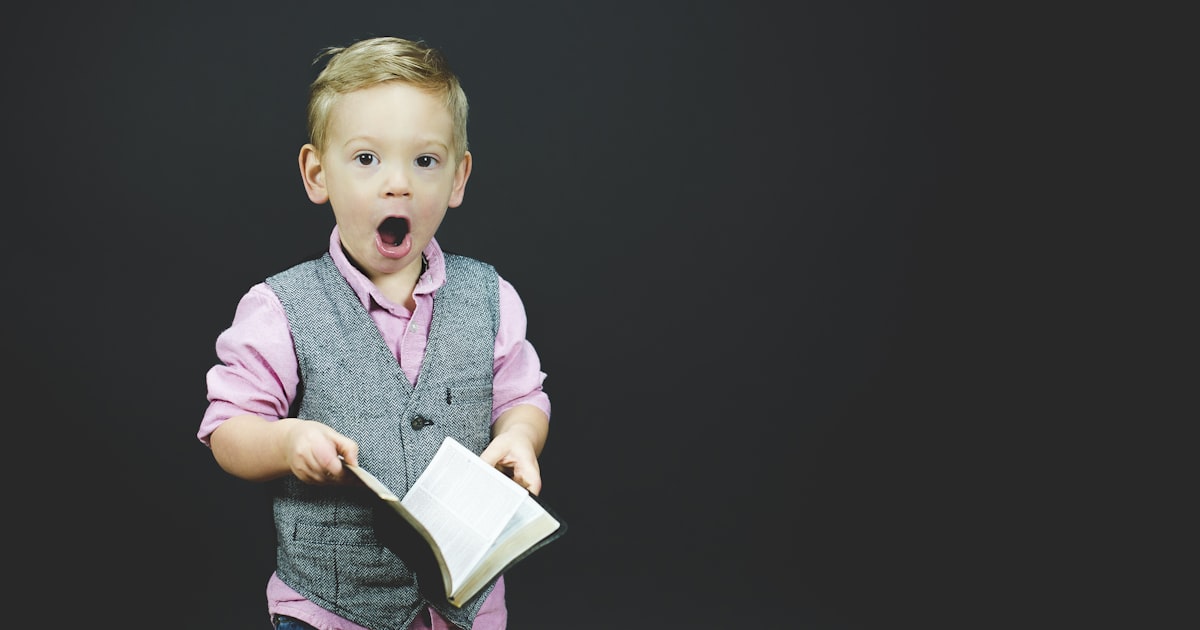 Child holding a book with a surprised expression